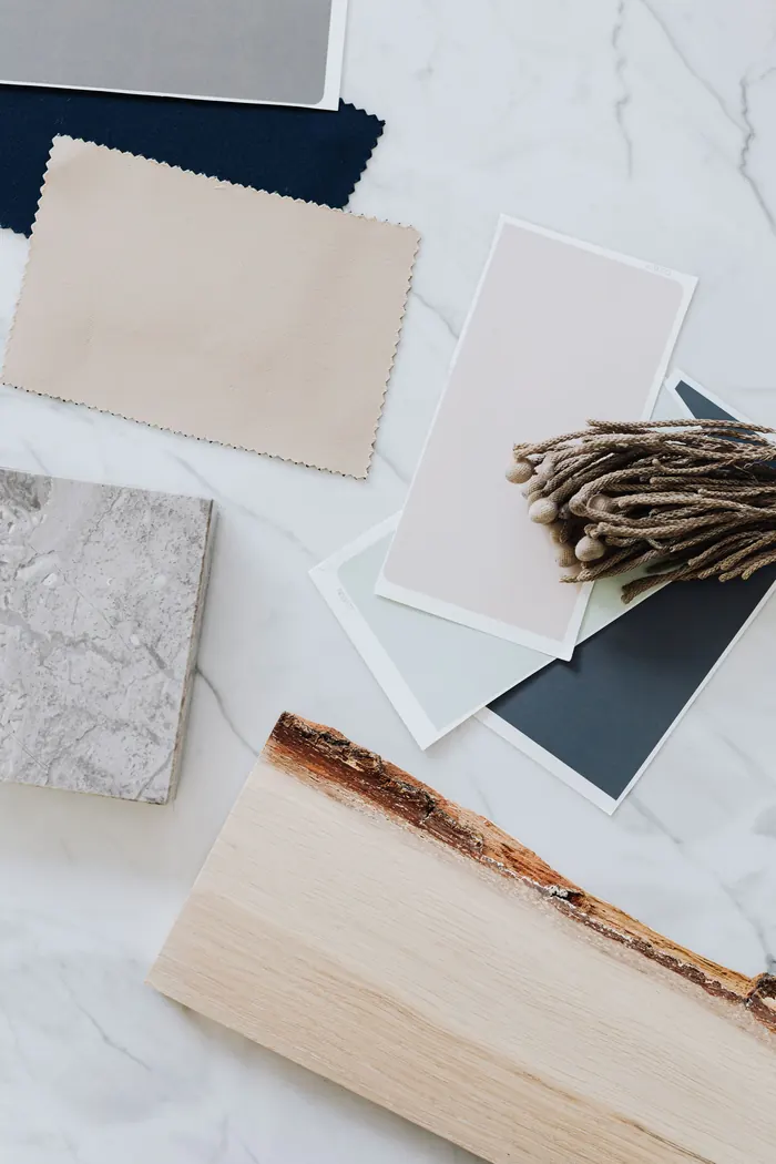 Material samples on a marble table: fabric, plaster, stone and a slab of raw-edged oak.