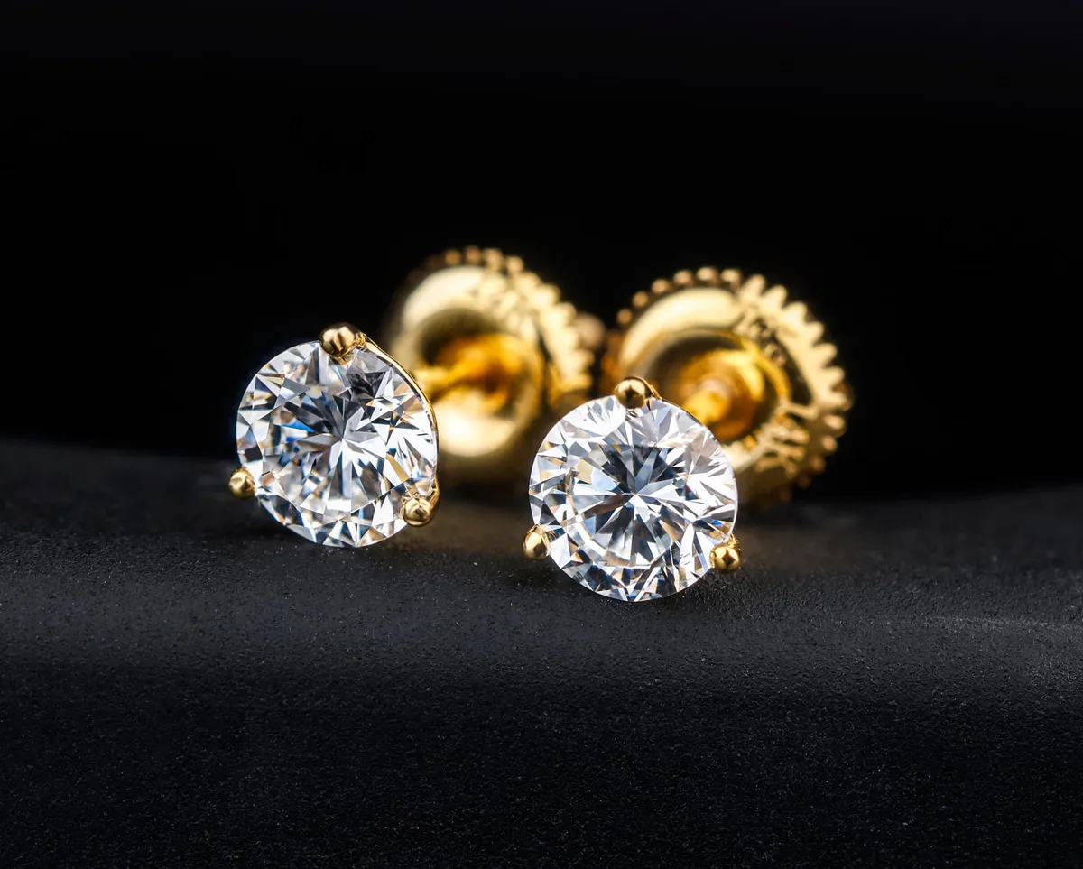A pair of round diamond studs with gold screw backs.