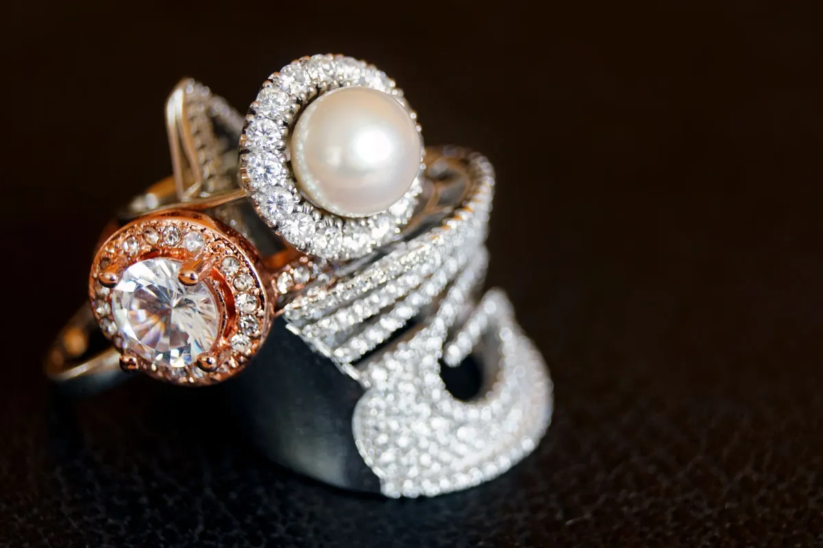 A pearl ring stacked with a diamond halo ring and a pavé band.
