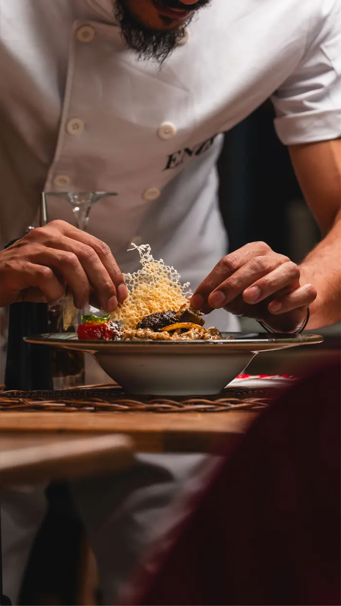 A cook finishing a plate with a garnish.