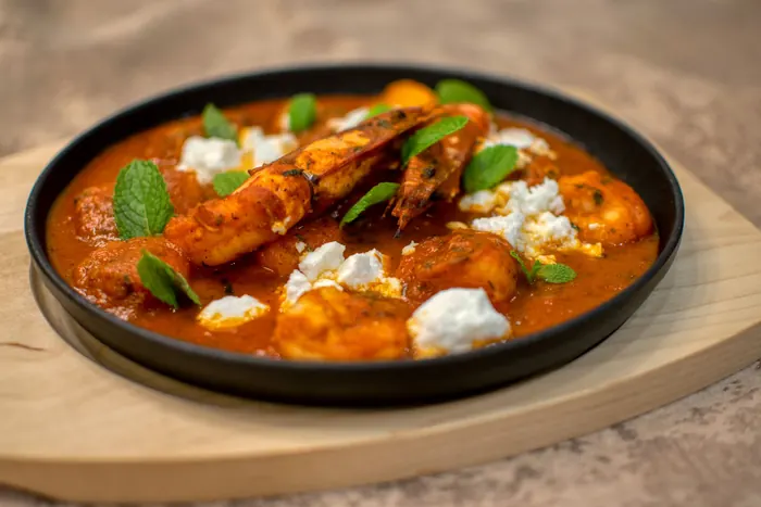 Prawn curry in a black pan, finished with mint.